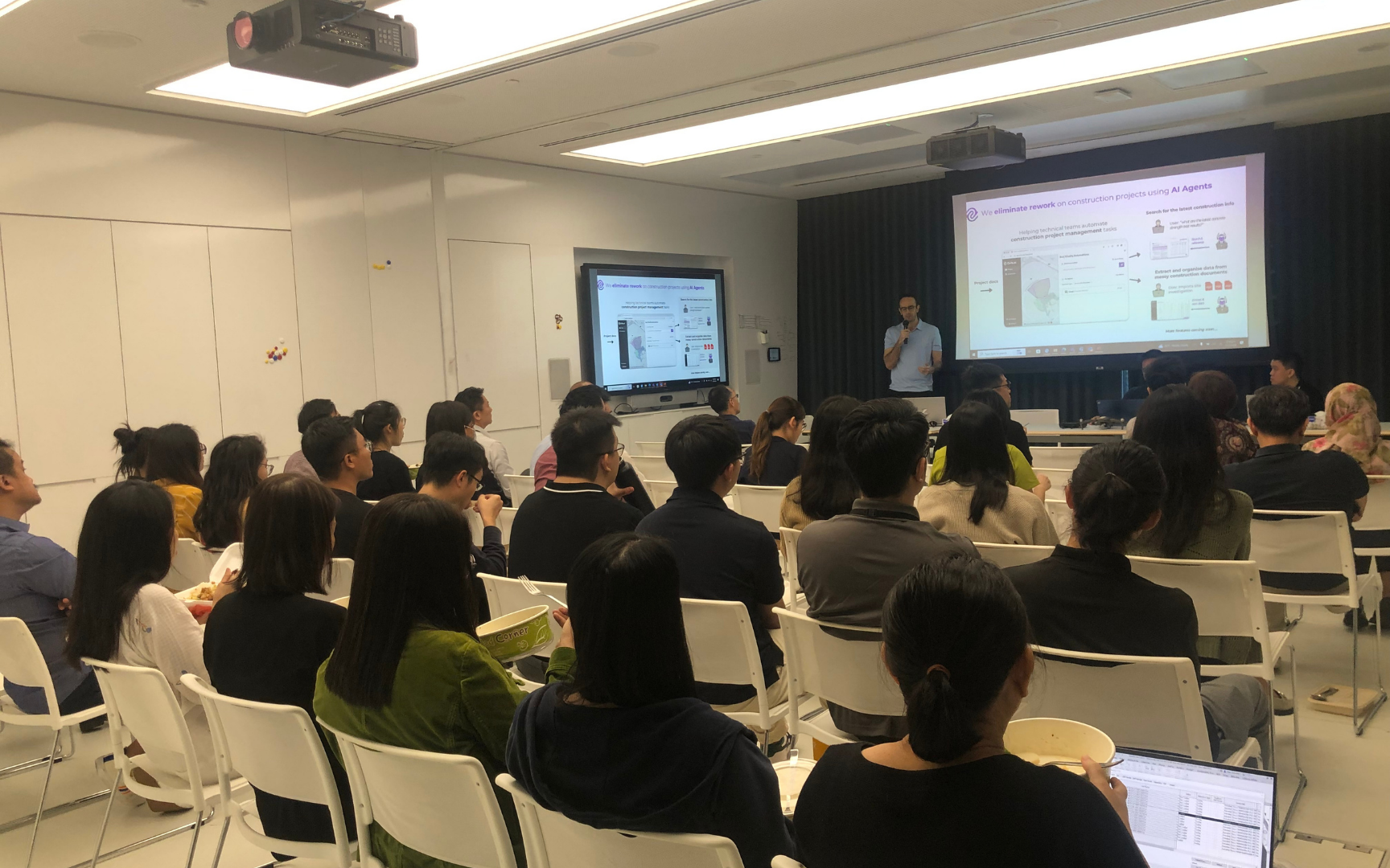 Audience watching the 'We eliminate rework on construction projects using AI Agents' slide